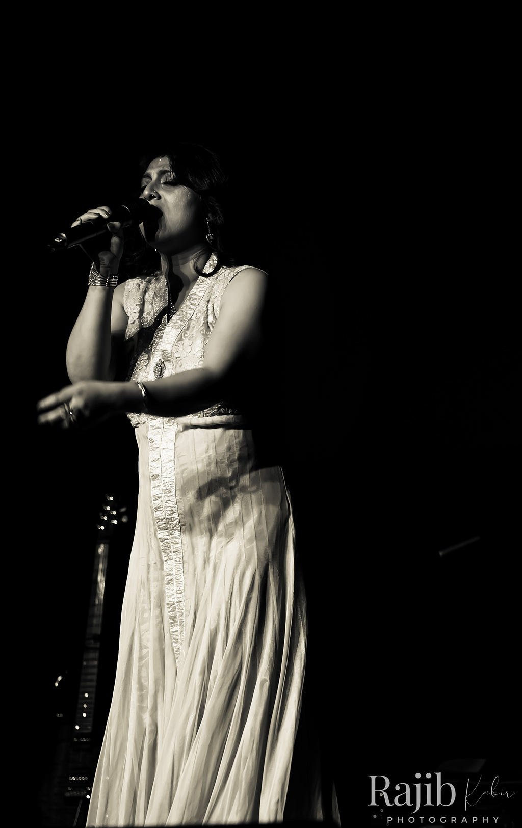 A powerful black and white image of a female singer passionately performing on stage with a microphone.