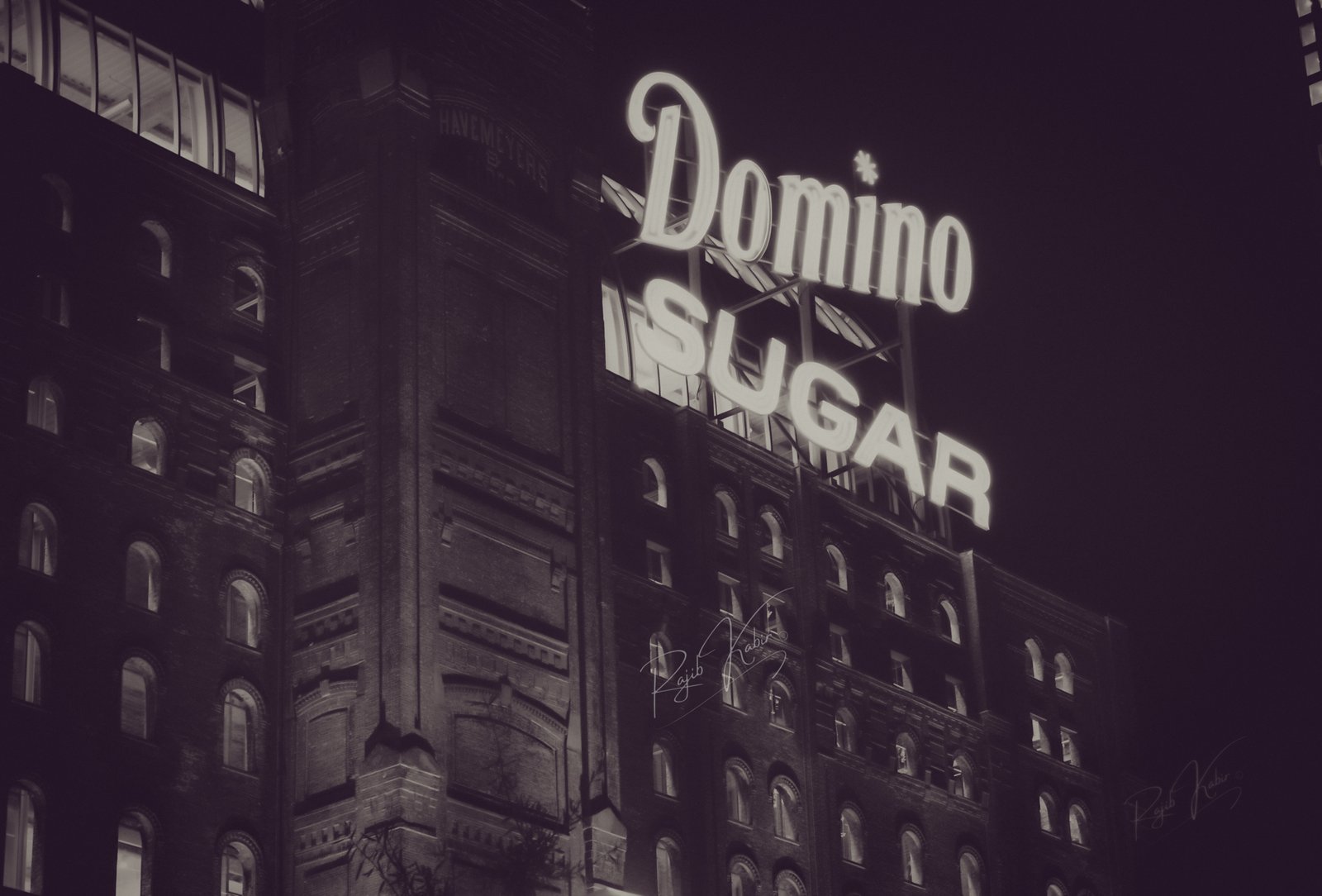 The glowing Domino Sugar Factory neon sign at night.