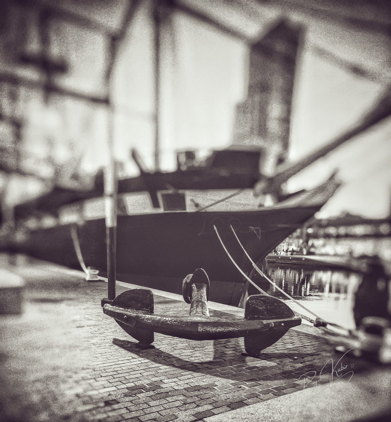 A historic ship docked with a large iron anchor in the foreground.