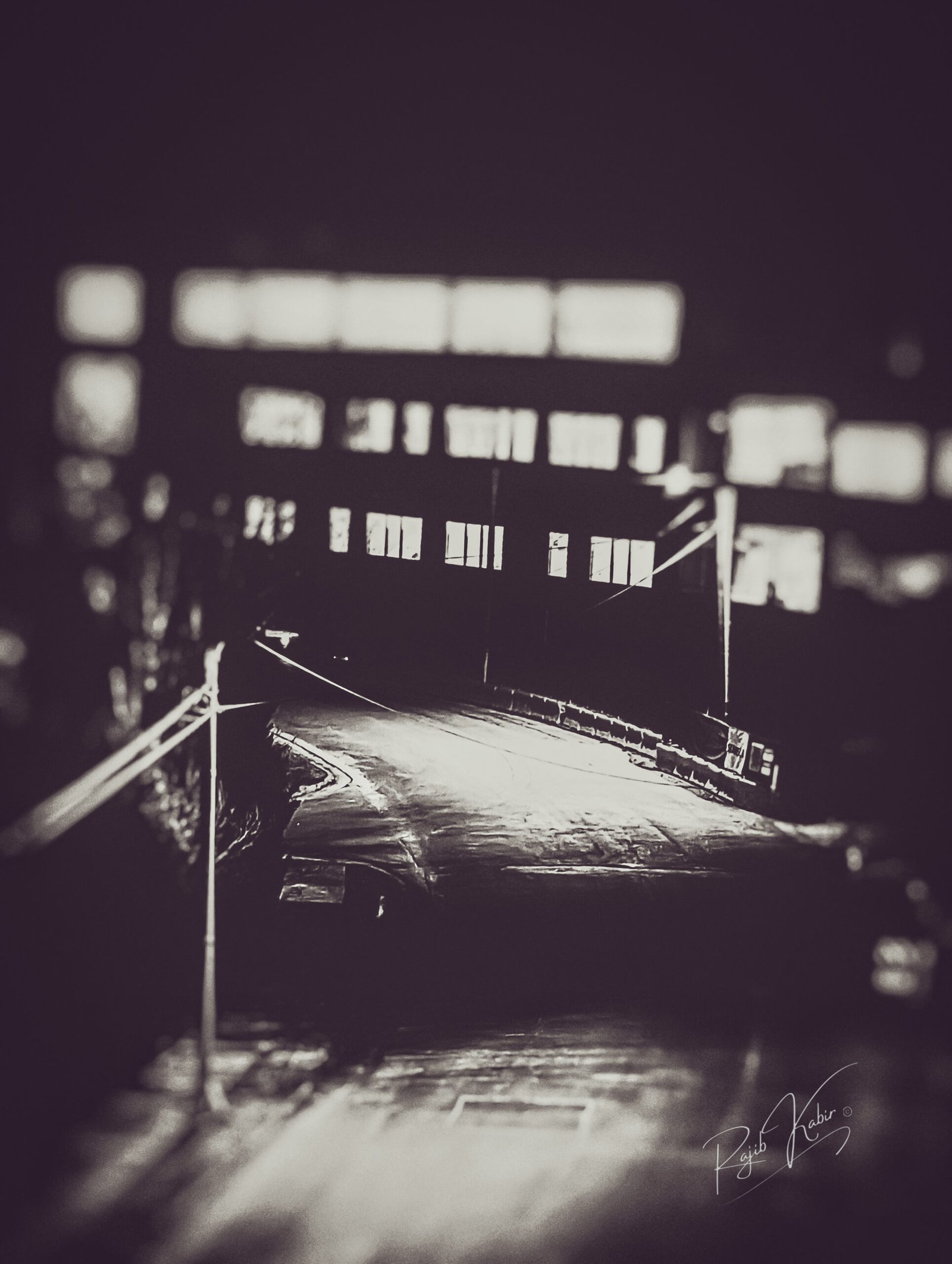 A dark and moody night street scene with illuminated windows and deep shadows.