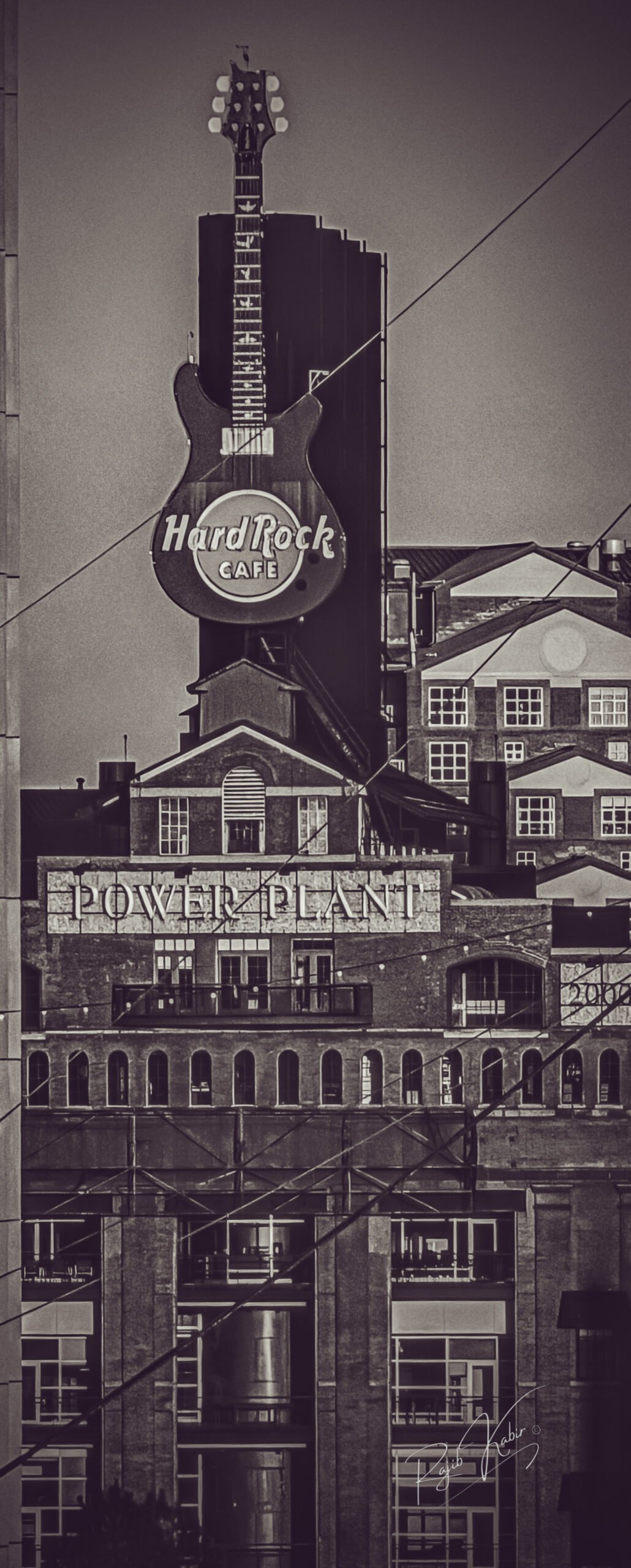 The iconic Hard Rock Cafe guitar sign glowing in an urban setting at night.