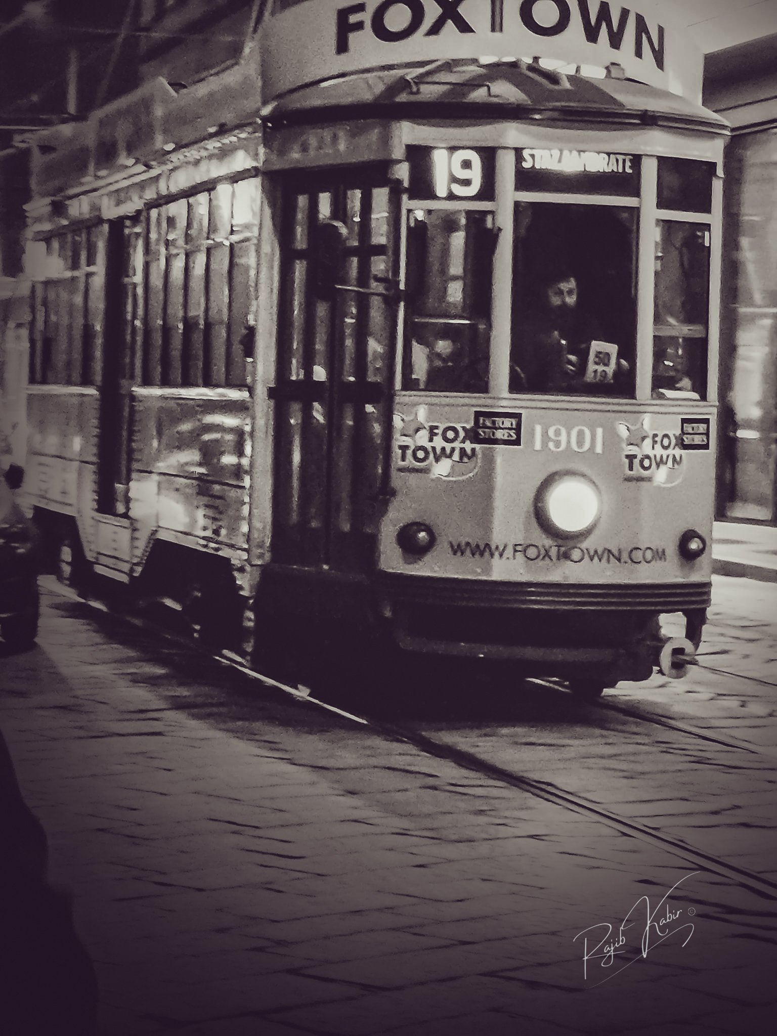 A vintage tram moving through the streets, captured in black and white.