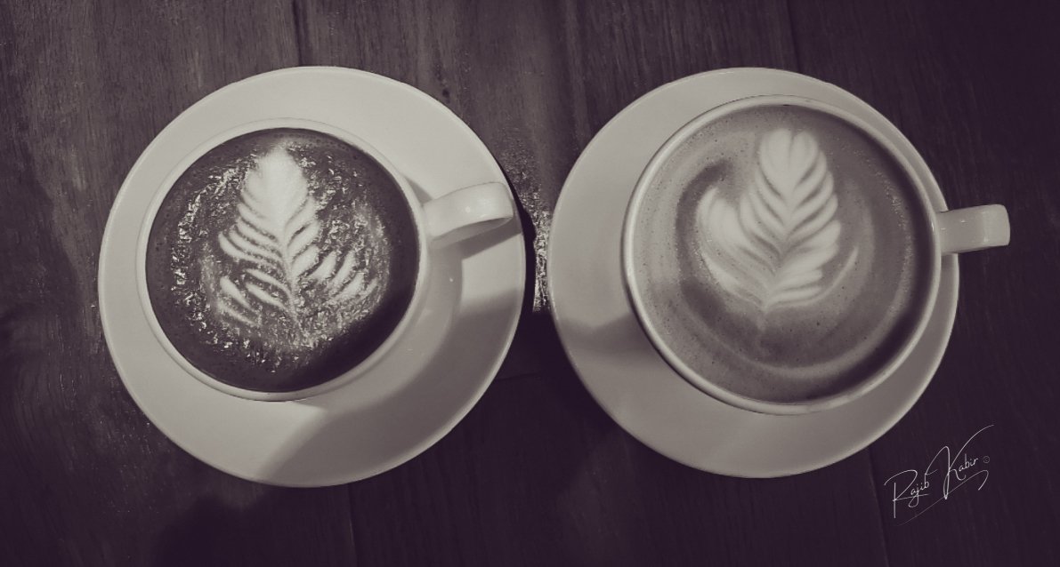 Two beautifully crafted coffee lattes with artistic foam designs.